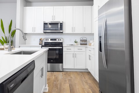 A modern kitchen with white cabinets and stainless steel appliances.