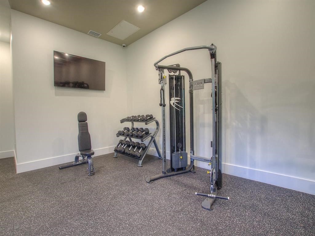 a gym with weights and a tv in the corner of a room