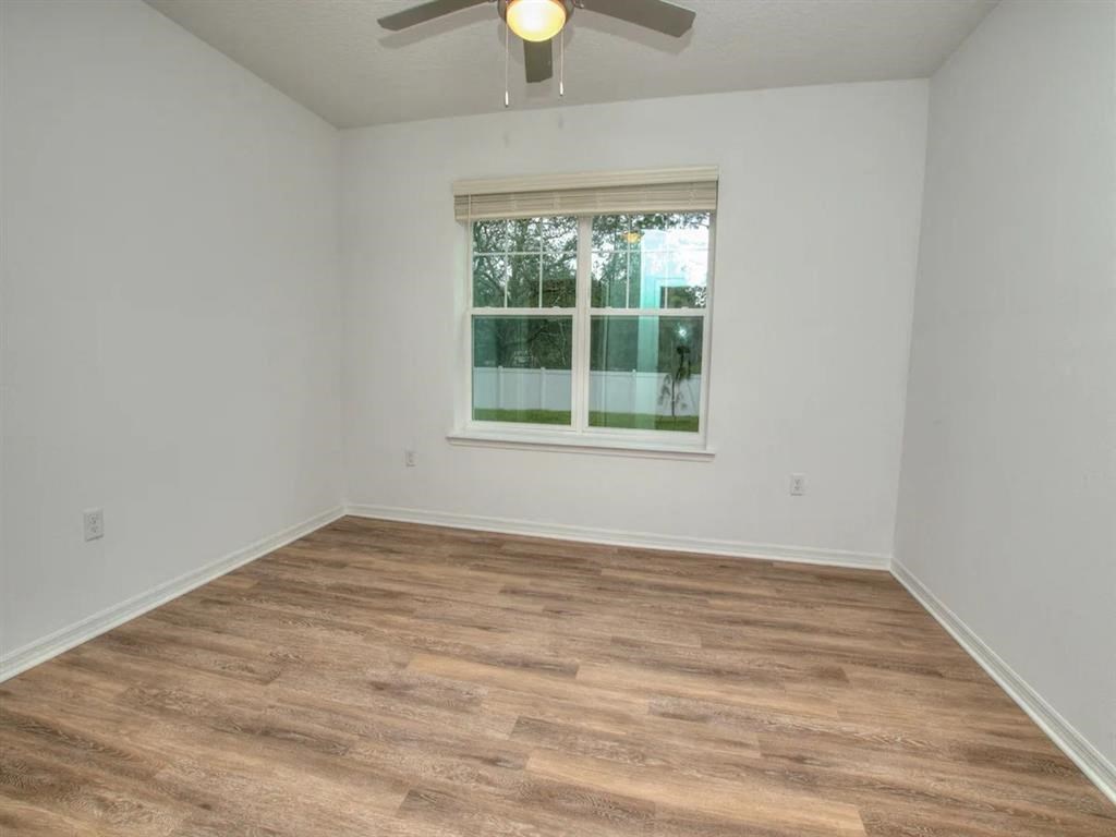 an empty room with a window and a ceiling fan