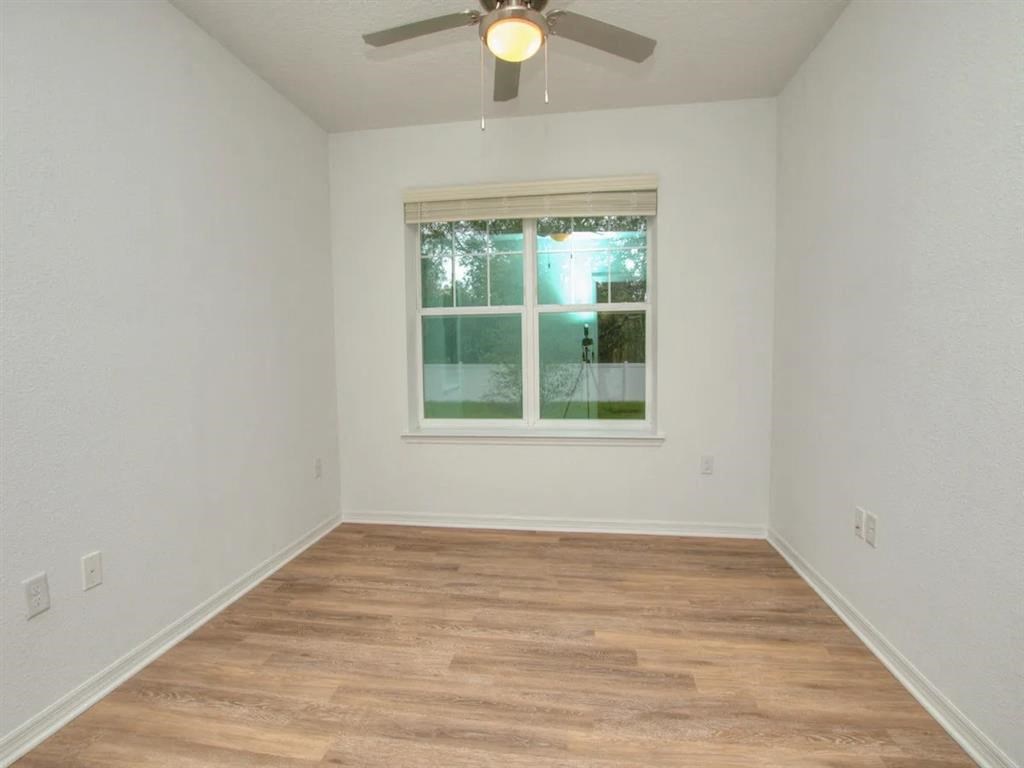 an empty room with a window and a ceiling fan