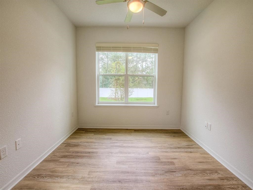 an empty room with a window and a ceiling fan