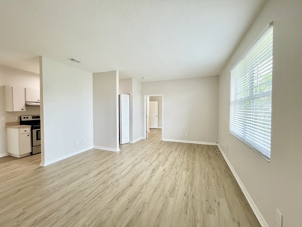 A spacious room with light wood flooring and white walls.