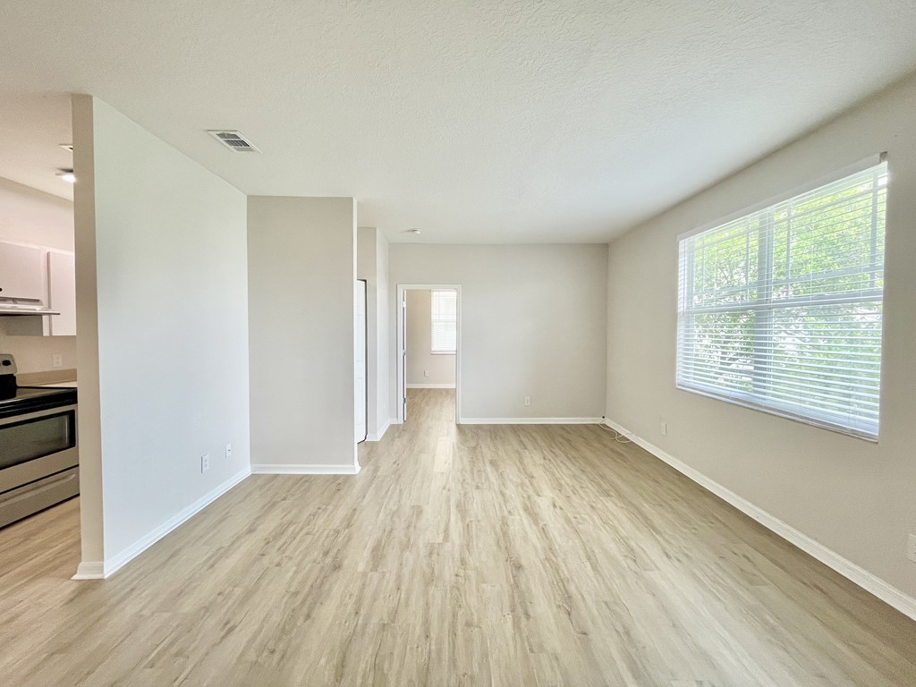 A spacious room with light wood flooring and white walls.