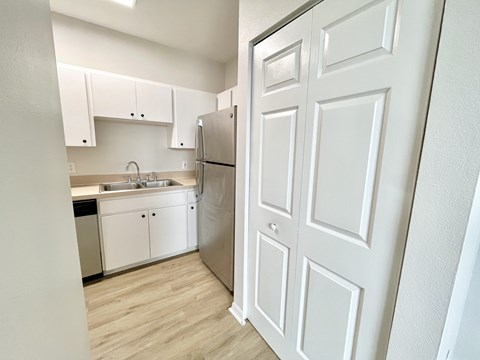 A white kitchen with a refrigerator and sink.