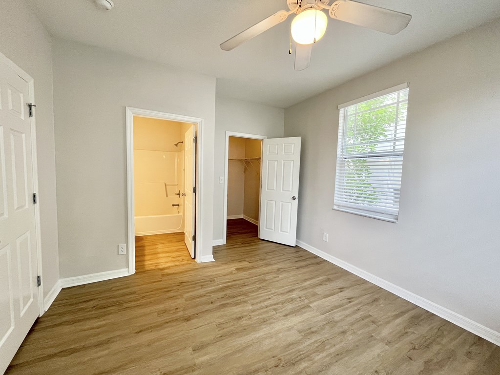 A room with a ceiling fan and a window with blinds.