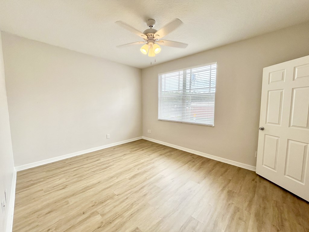 A room with a ceiling fan and wooden flooring.