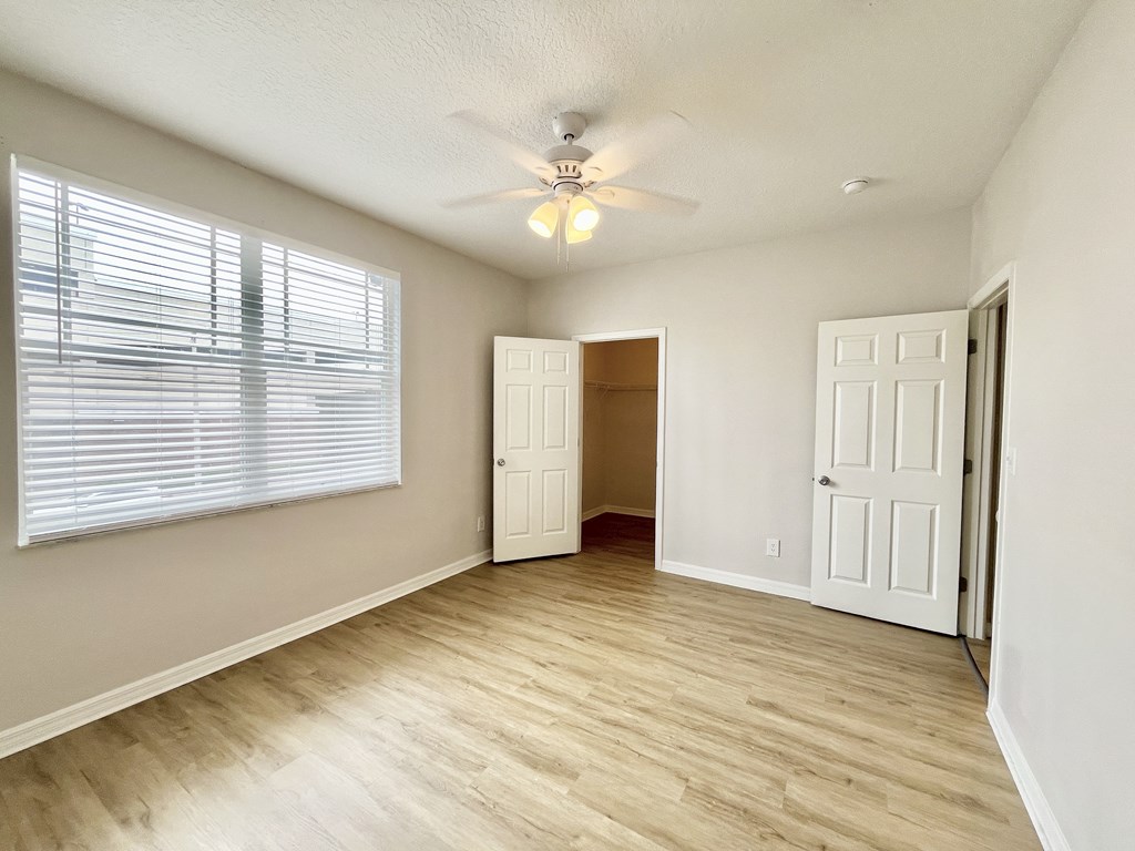 A room with a ceiling fan and a window with blinds.