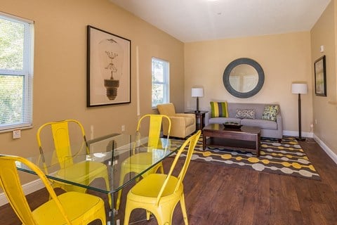 a living room with a glass table and yellow chairs
