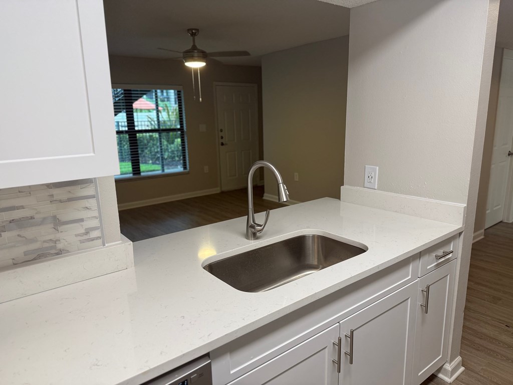 A kitchen with a white countertop and a stainless steel sink.