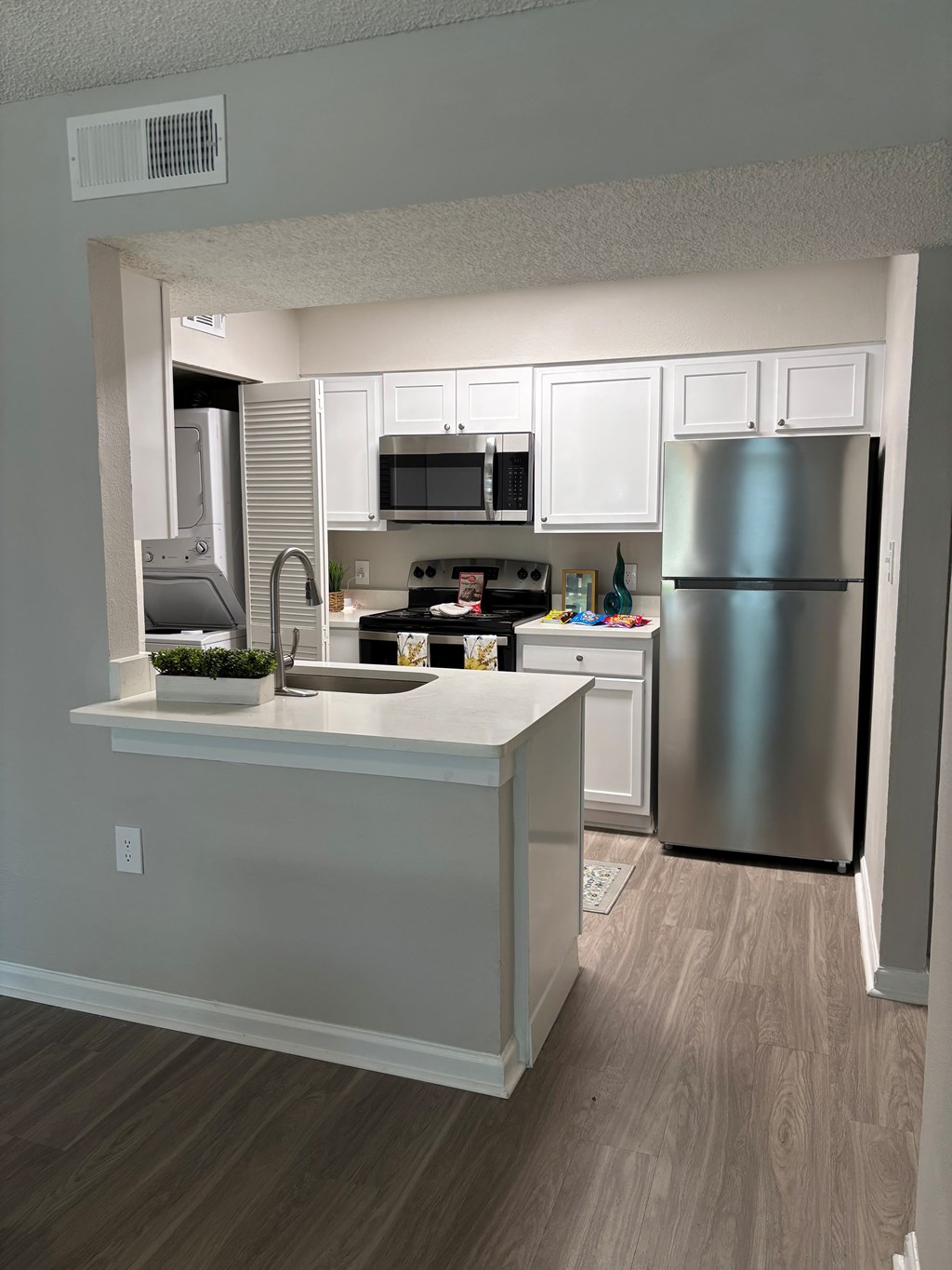 A kitchen with a refrigerator, microwave, and oven.