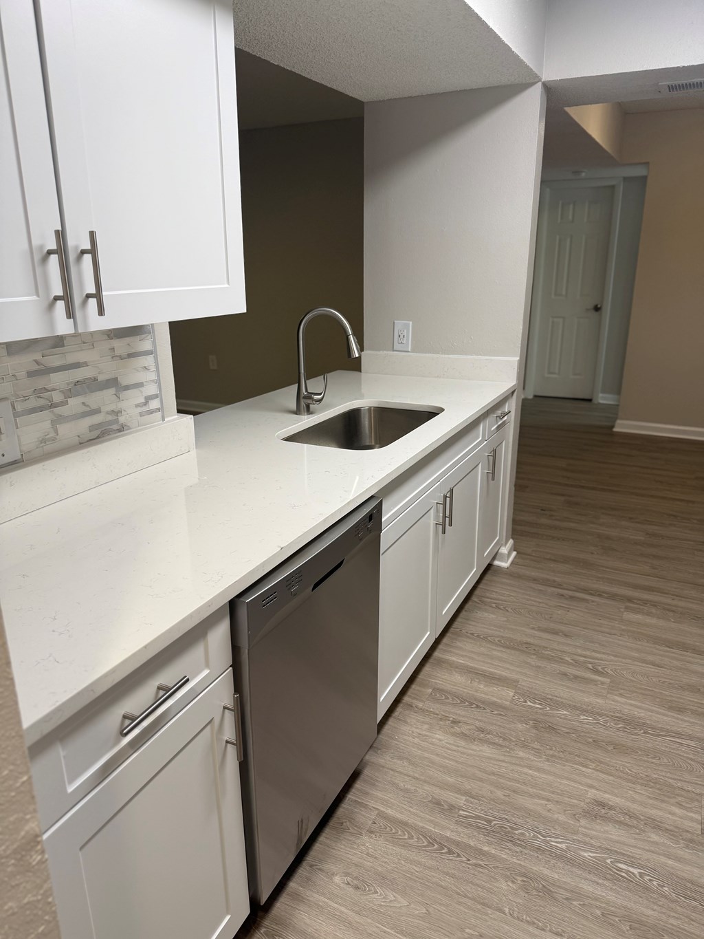 A kitchen with white cabinets and a stainless steel dishwasher.