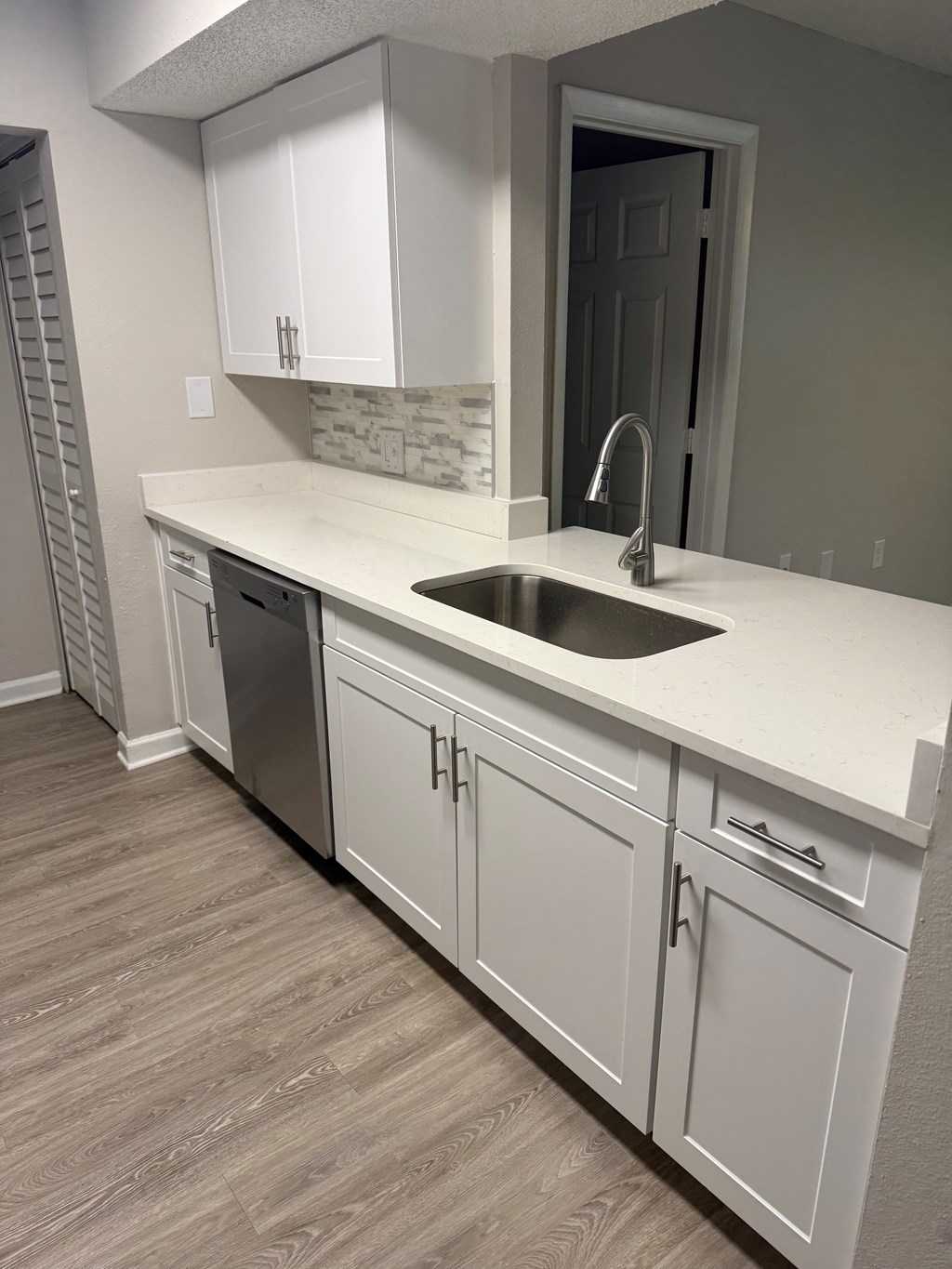 A kitchen with white cabinets and a sink.