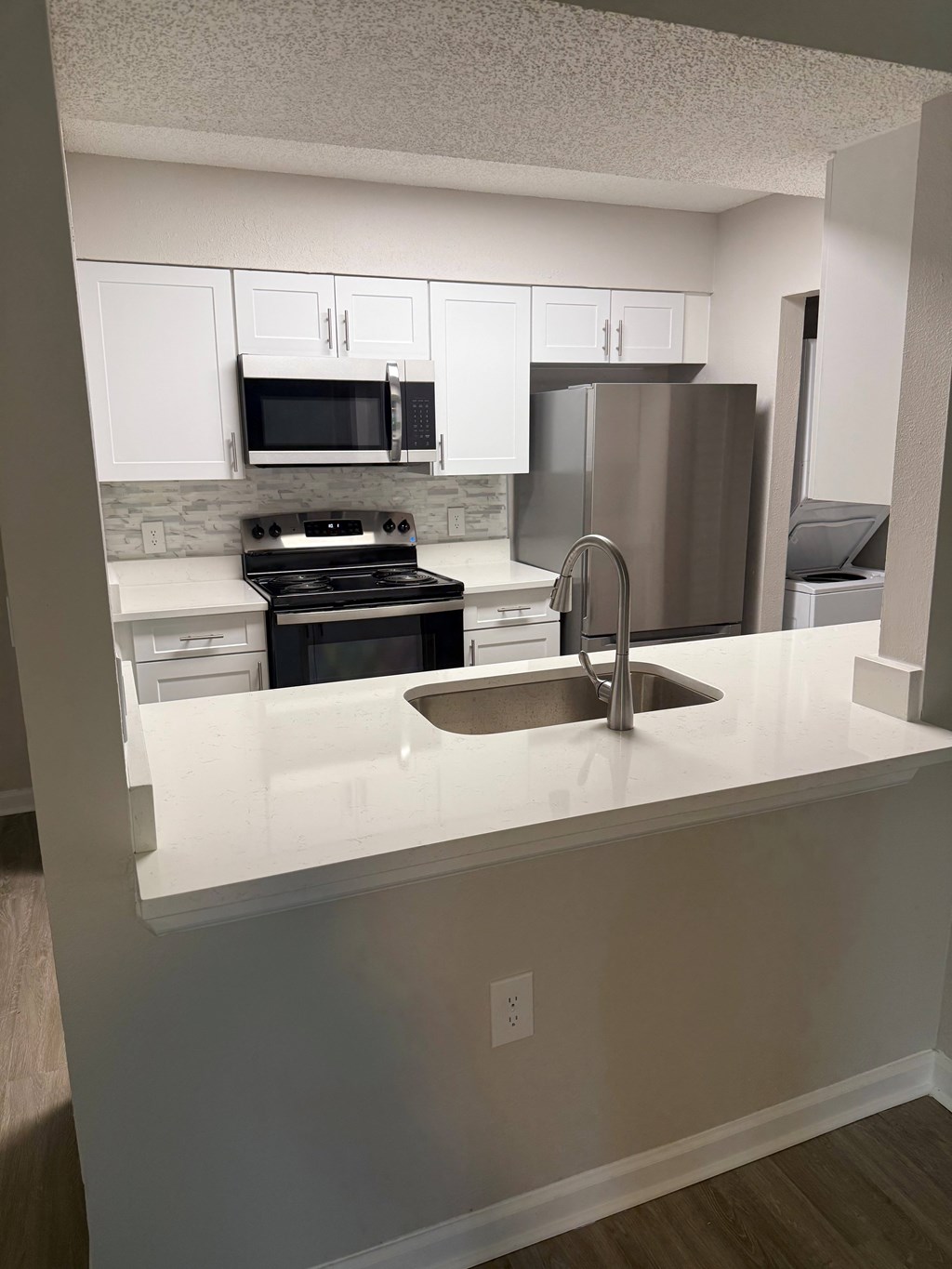 A kitchen with white cabinets and a stainless steel refrigerator.