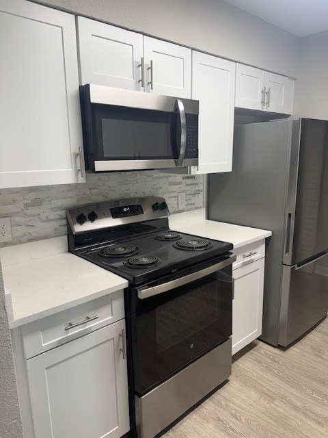 A kitchen with a black stove top oven and white cabinets.