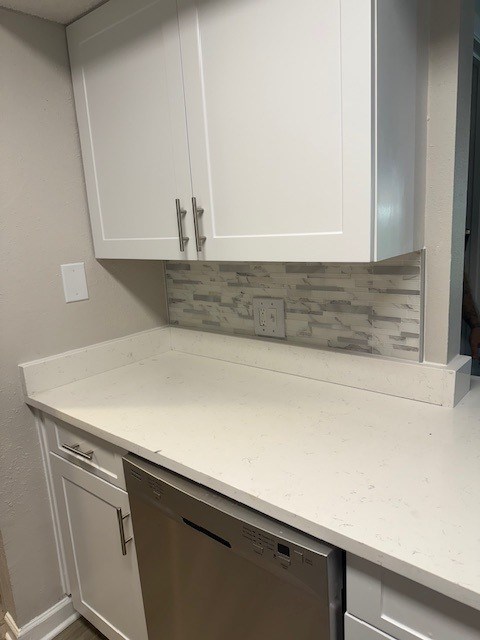 A kitchen with white cabinets and a washer and dryer.