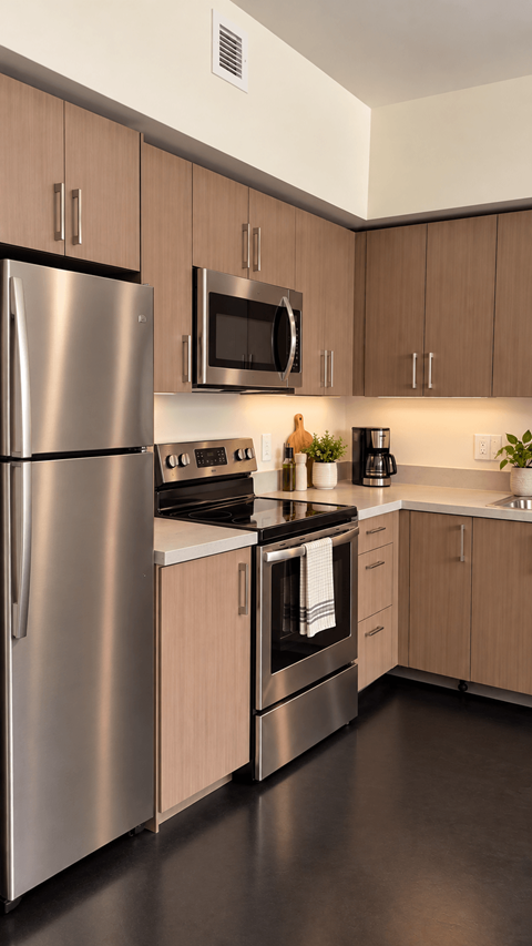 A modern kitchen with a stainless steel refrigerator and wooden cabinets at Ambar Station Apartments, Florida