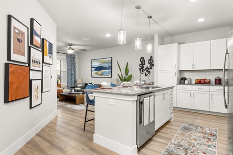 an open kitchen and living room with white cabinets and a large island
