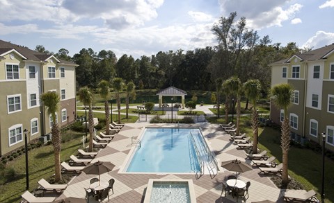A swimming pool surrounded by palm trees and lounge chairs.