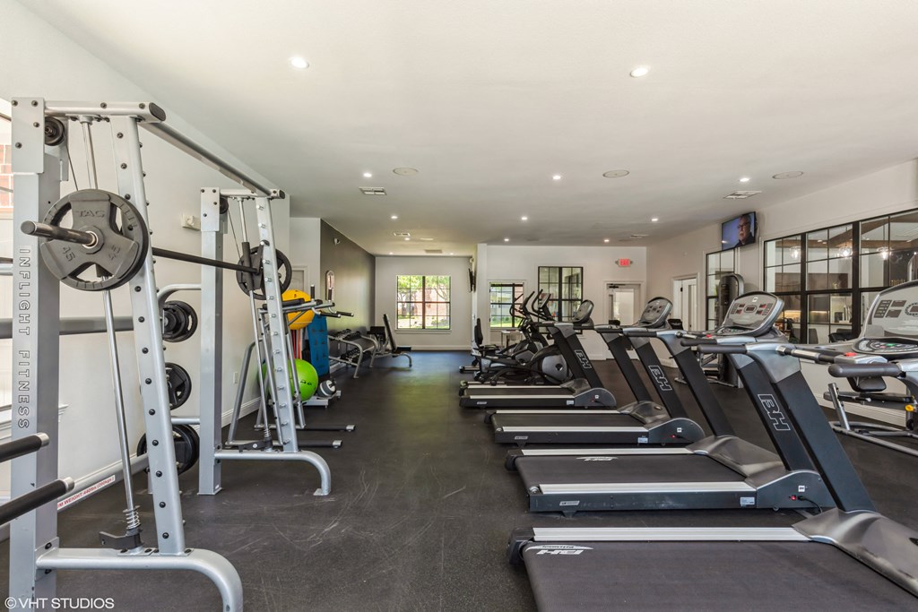 a gym with cardio equipment and weights on the floor