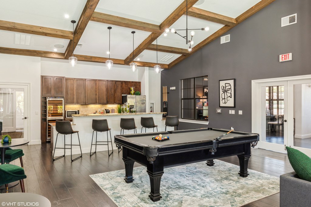 an open living room with a pool table and a kitchen with a bar