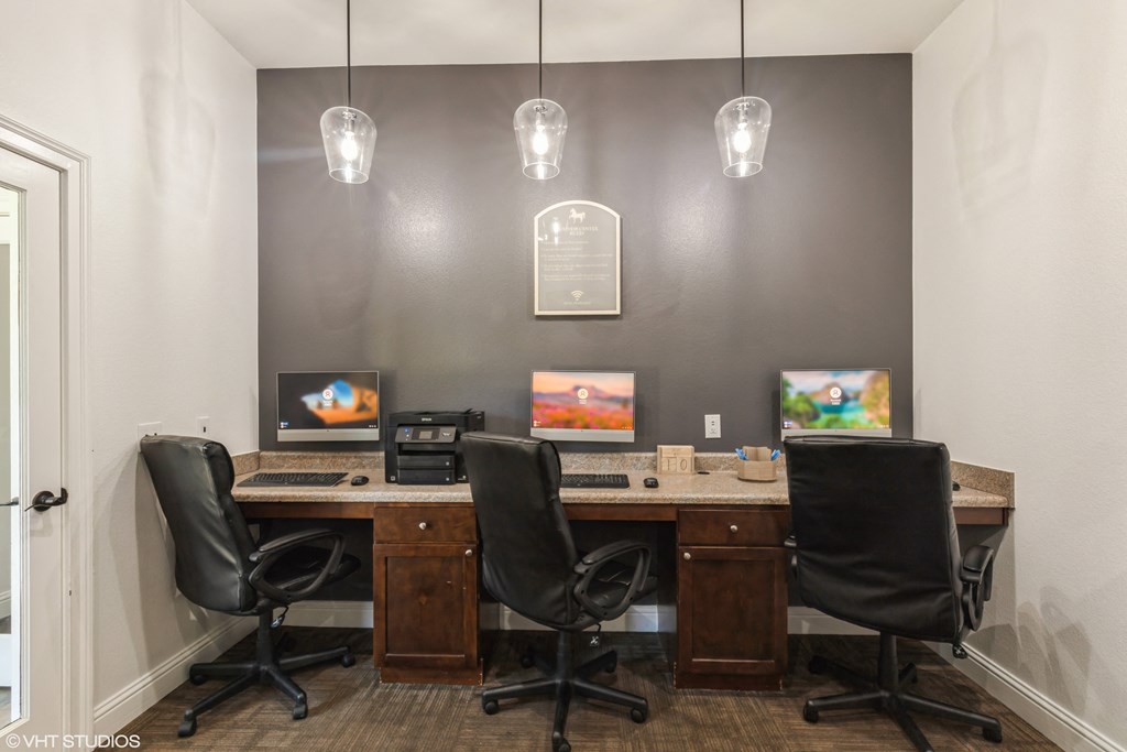two desks with chairs in a room with two computer monitors