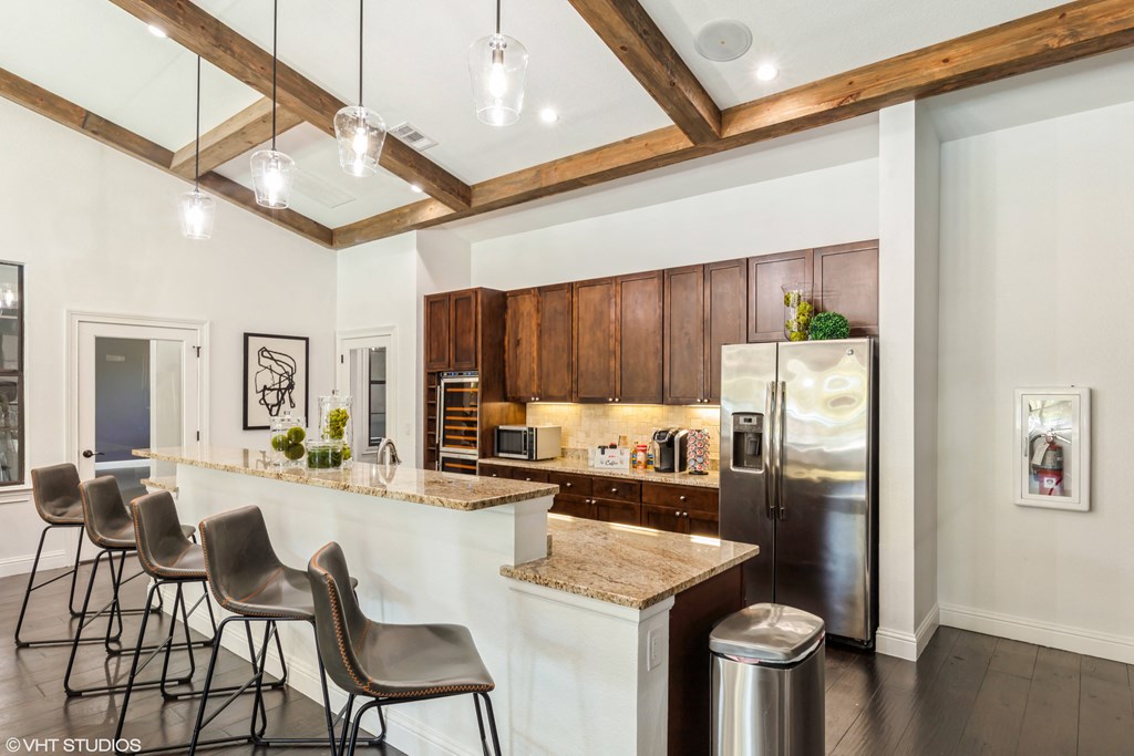 a kitchen with a bar and chairs and a refrigerator