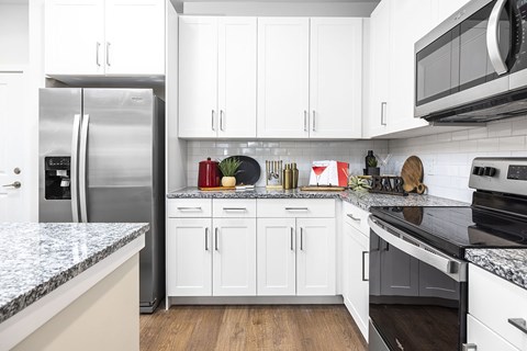 A kitchen with white cabinets and a granite countertop.