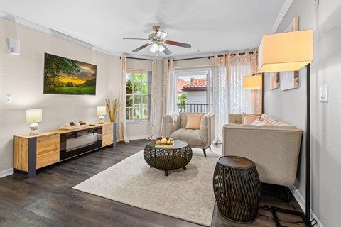 A living room with a ceiling fan and a painting on the wall.
