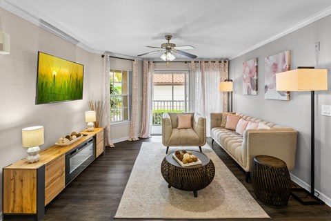 A living room with a brown floor and a painting of a sunrise on the wall.