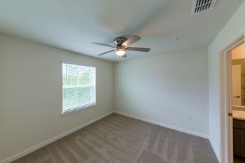 an empty bedroom with a ceiling fan