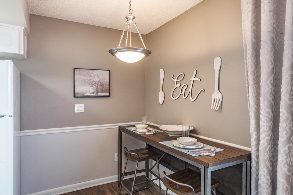 A dining area with a table set for two and a framed picture on the wall.