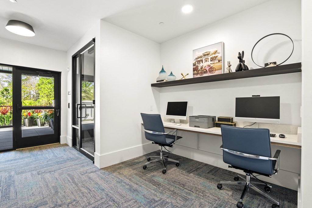 a white office with two desks and two computer monitors