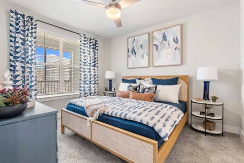 Bedroom with blue accent pillows and woven headboard at Longleaf at St. Johns Apartments, St. Johns, Florida