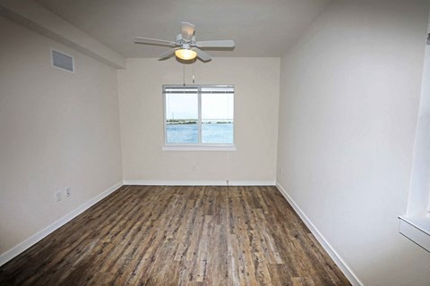 an empty living room with a ceiling fan and a window