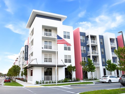 A white building with a red and blue stripe on the side and an American flag hanging from the balcony.