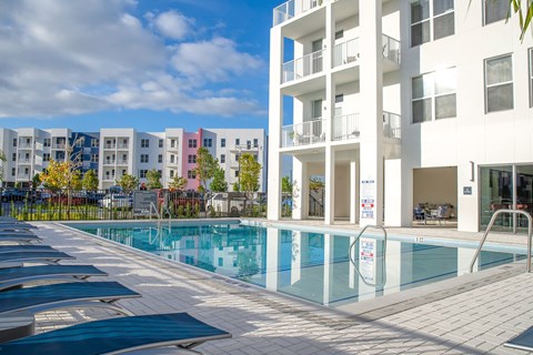 A swimming pool in front of a white building with a blue sky in the background.