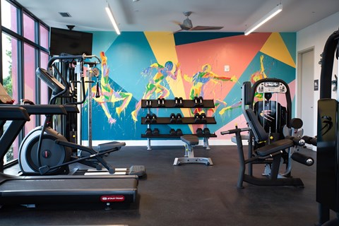 Fitness center with colorful athletic mural at Ambar Trail Apartments, Homestead, FL