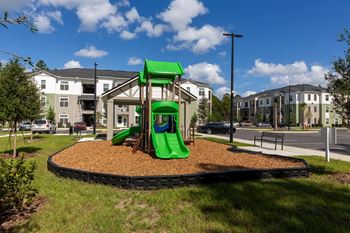a playground with a green slide in front of an apartment building