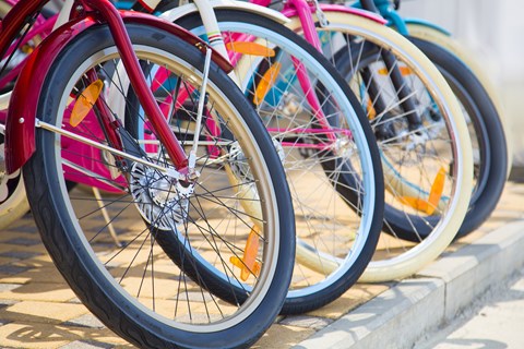 A row of bicycles with different colored frames are parked next to each other.