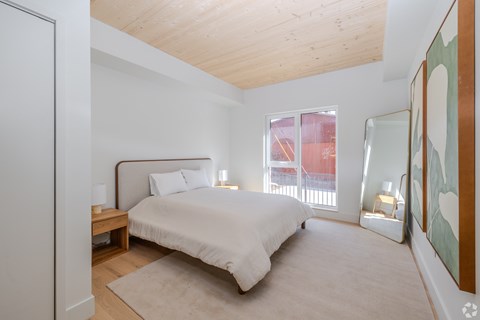 A bedroom with a bed, nightstands, and a painting on the wall.