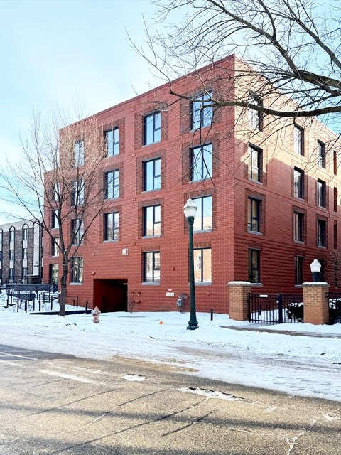 A red brick building with a black fence in front.