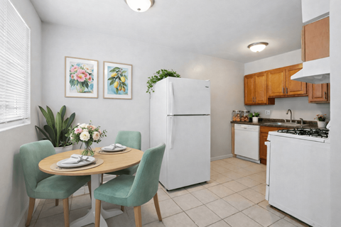 A kitchen with a table and chairs and a fridge.