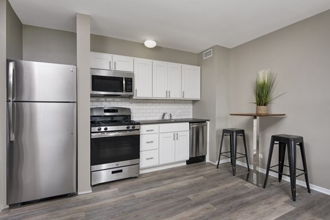 A kitchen with a refrigerator, stove, and bar stools.
