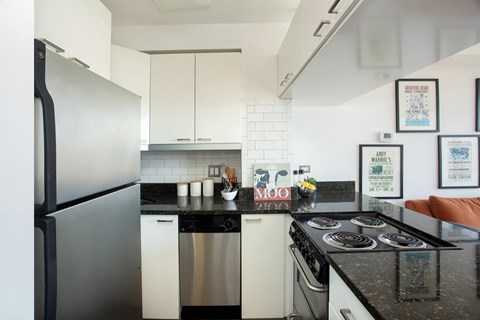 A kitchen with a black counter top and white cabinets.