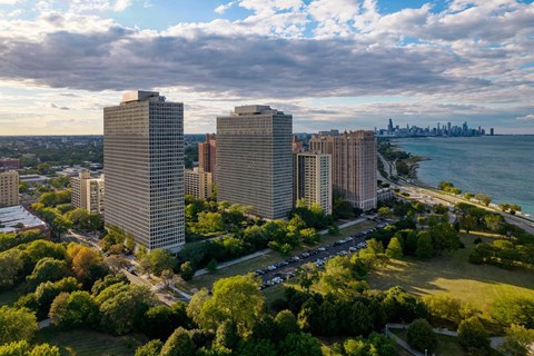 A cityscape with buildings, trees, and a body of water in the background.