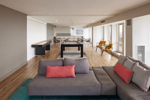 A living room with a grey couch and a green rug.