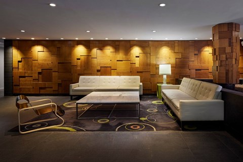A modern living room with a white sofa and a wooden backdrop.