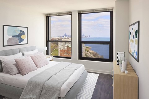 A bedroom with a large bed and a view of the city through the window.