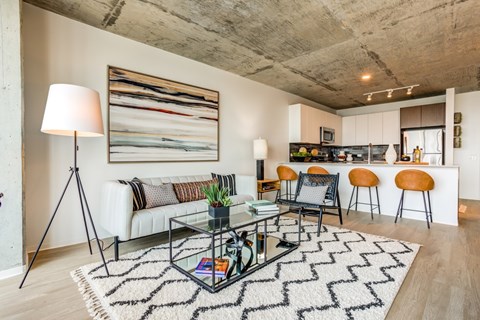 A modern living room with a glass coffee table and a large abstract painting on the wall.