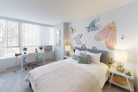 A bedroom with a large bed and a butterfly mural on the wall.